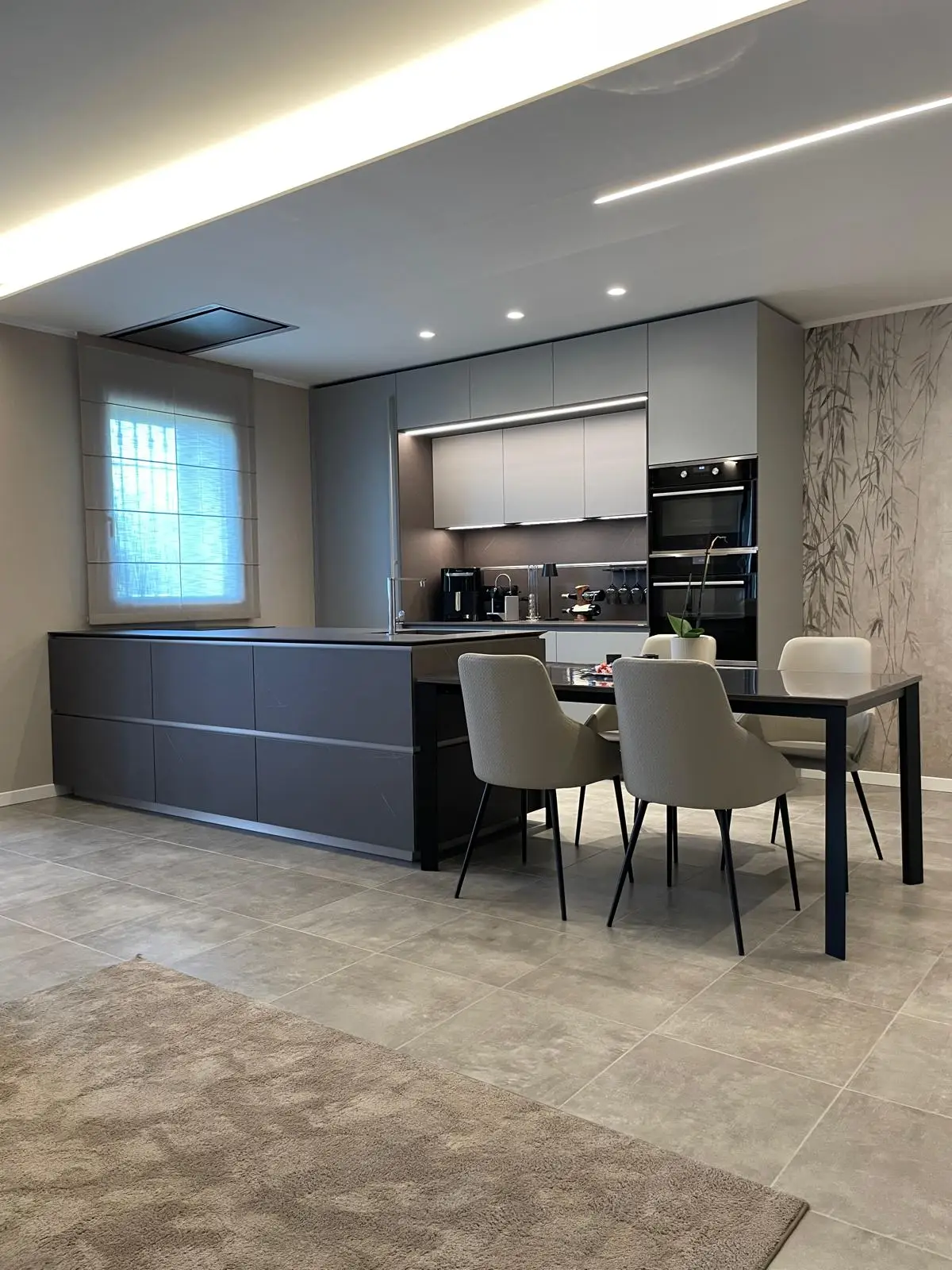 Cucina Ernestomeda realizzata su misura con isola, zona pranzo e illuminazione studiata durante la progettazione dell'ambiente.